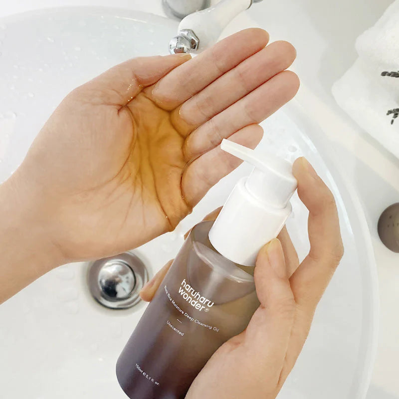 Haruharu Wonder Black Rice Moisture Deep Cleansing Oil being dispensed into hand, showing its rich, nourishing oil texture ideal for removing makeup and impurities