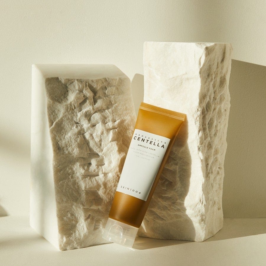 SKIN1004 Centella Ampoule Foam cleanser styled between textured stone blocks in warm lighting
