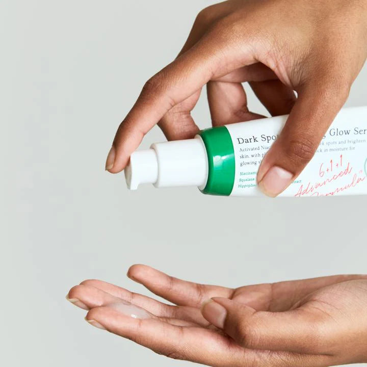 Applying AXIS-Y Dark Spot Correcting Glow Serum onto hand, featuring a green and white tube with niacinamide for brightening and dark spot treatment.