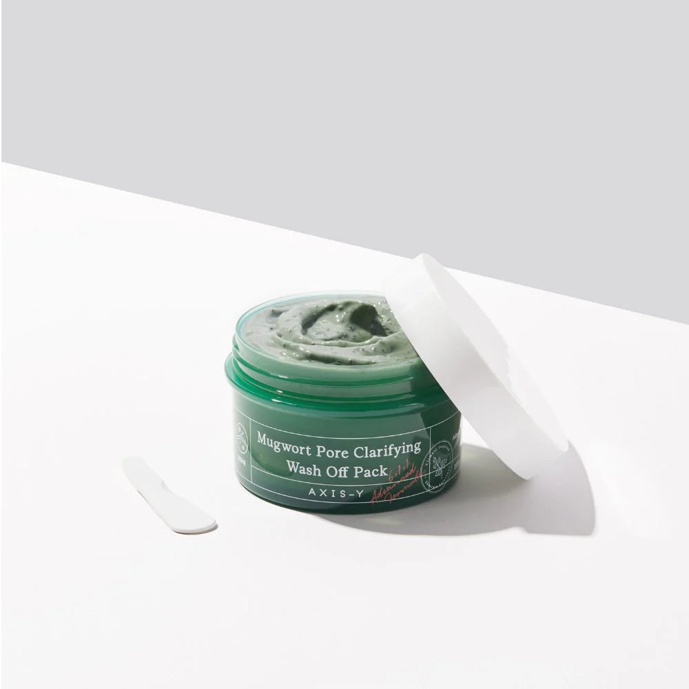 Open jar of AXIS-Y Mugwort Pore Clarifying Wash Off Pack with spatula, showing creamy green texture ideal for soothing acne-prone, oily skin.