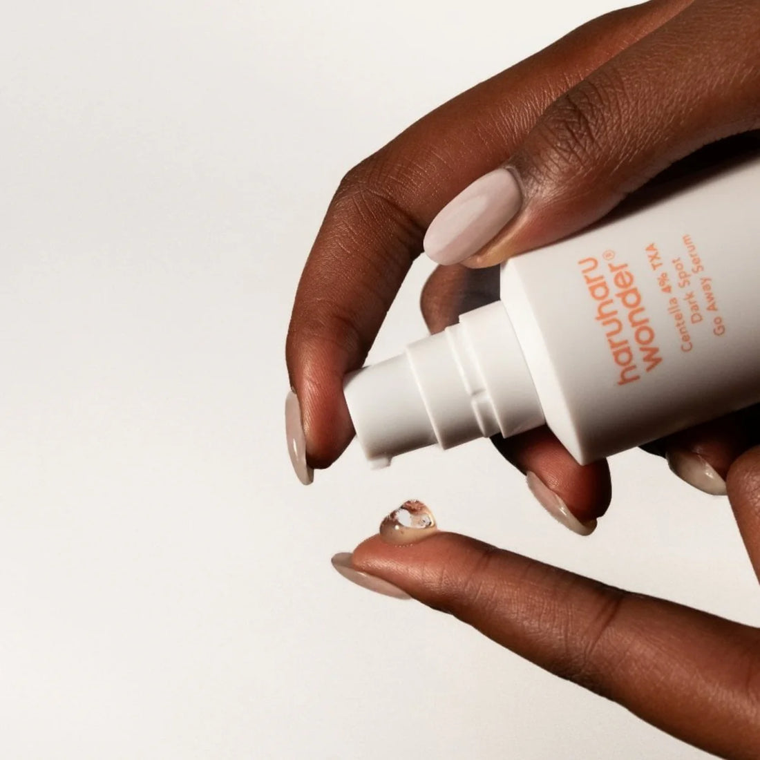 Close-up of hands applying Haruharu Wonder Centella 4% TXA Dark Spot Go Away Serum, a lightweight gel formula for brightening uneven skin tone and fading dark spots.