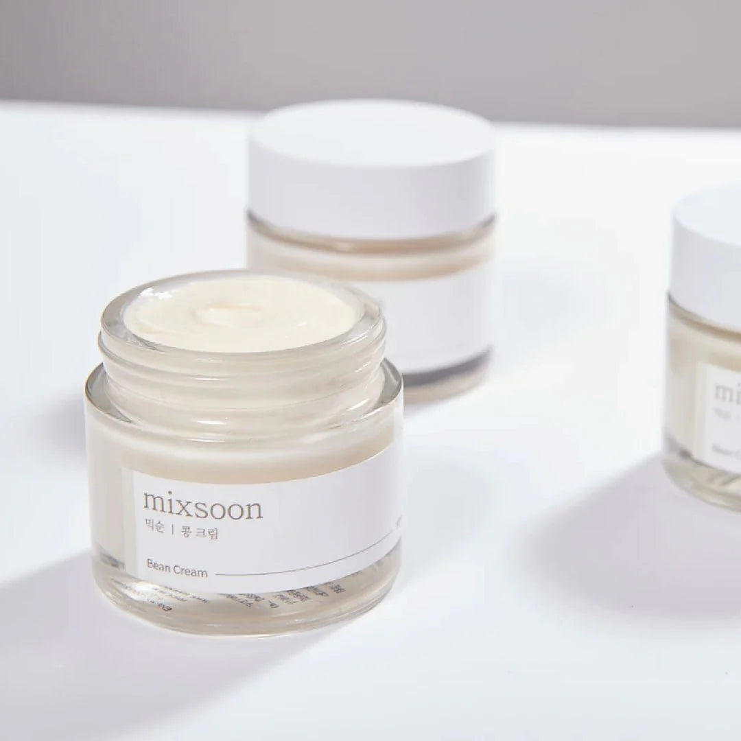 Mixsoon Bean Cream open jar with visible creamy texture, surrounded by minimalist skincare jars on a white surface.