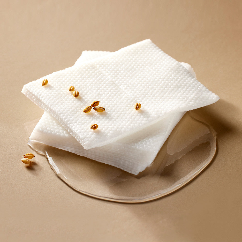 Textured skincare toner pads with visible essence and barley grains, highlighting nourishing ingredients in exfoliating facial pads.