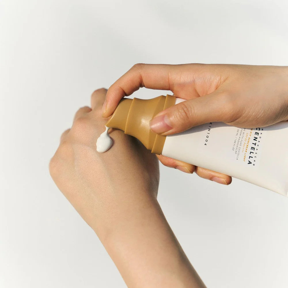 Applying SKIN1004 Centella sunscreen with creamy texture onto hand for texture demo