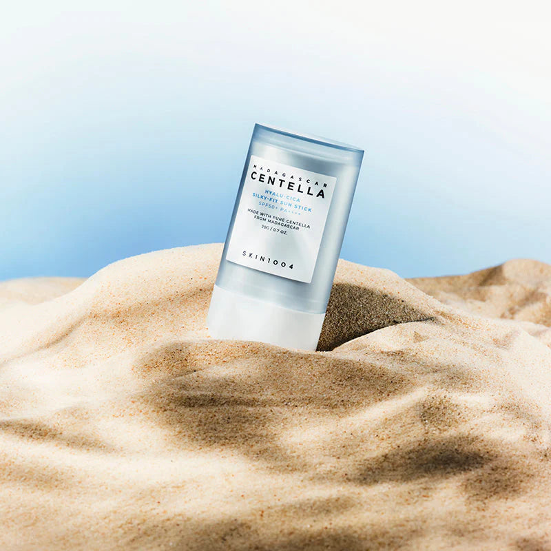 SKIN1004 Hyalu-Cica Silky-Fit Sun Stick SPF50+ PA++++ standing in beach sand with blue sky background