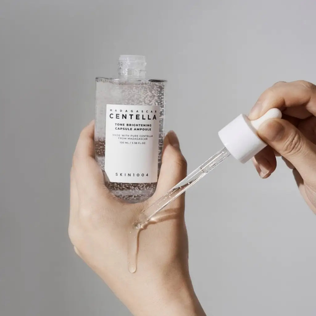 Applying SKIN1004 Centella Tone Brightening Capsule Ampoule to hand with clear dropper
