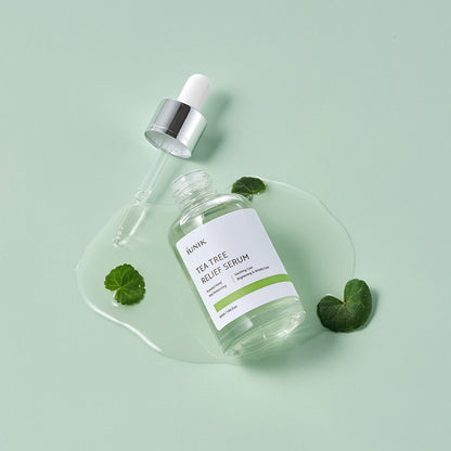 iUNIK Tea Tree Relief Serum bottle with dropper and centella leaves on a pastel green background – soothing Korean skincare for sensitive skin.